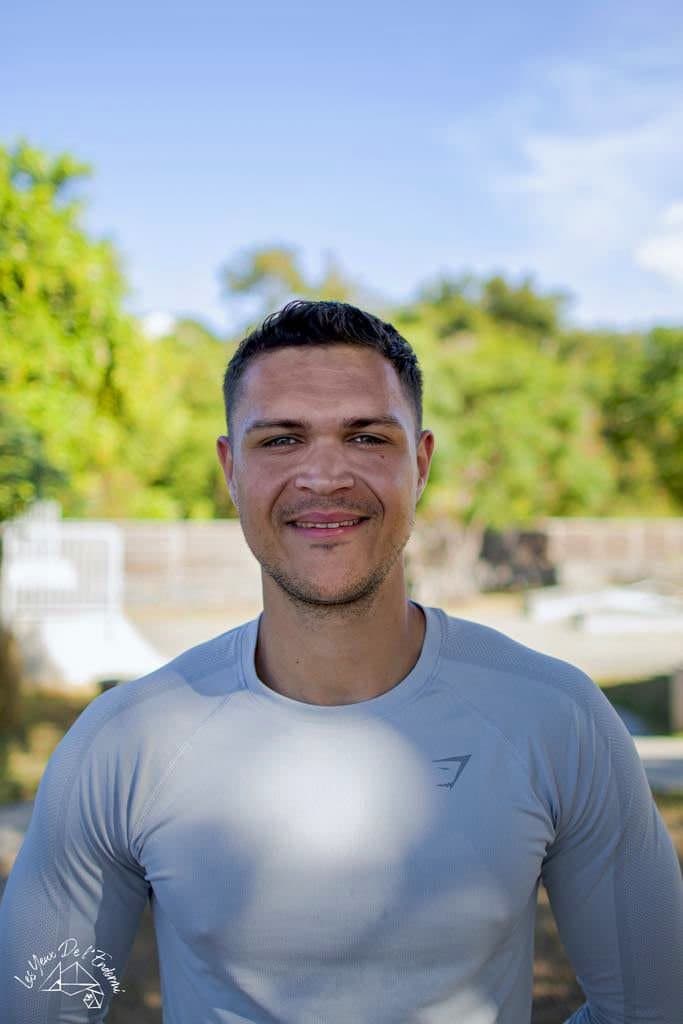Portrait de Ludovic en tenue de sport, souriant, en extérieur.
